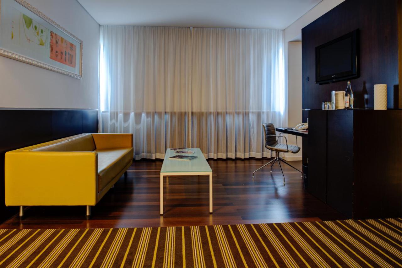 een woonkamer met een gele bank en een tafel bij VIP Grand Lisboa Hotel & Spa in Lissabon