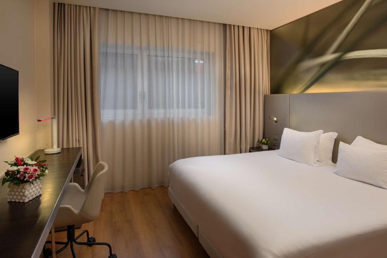 een hotelkamer met een groot bed en een bureau bij NH Orio al Serio Airport in Orio al Serio