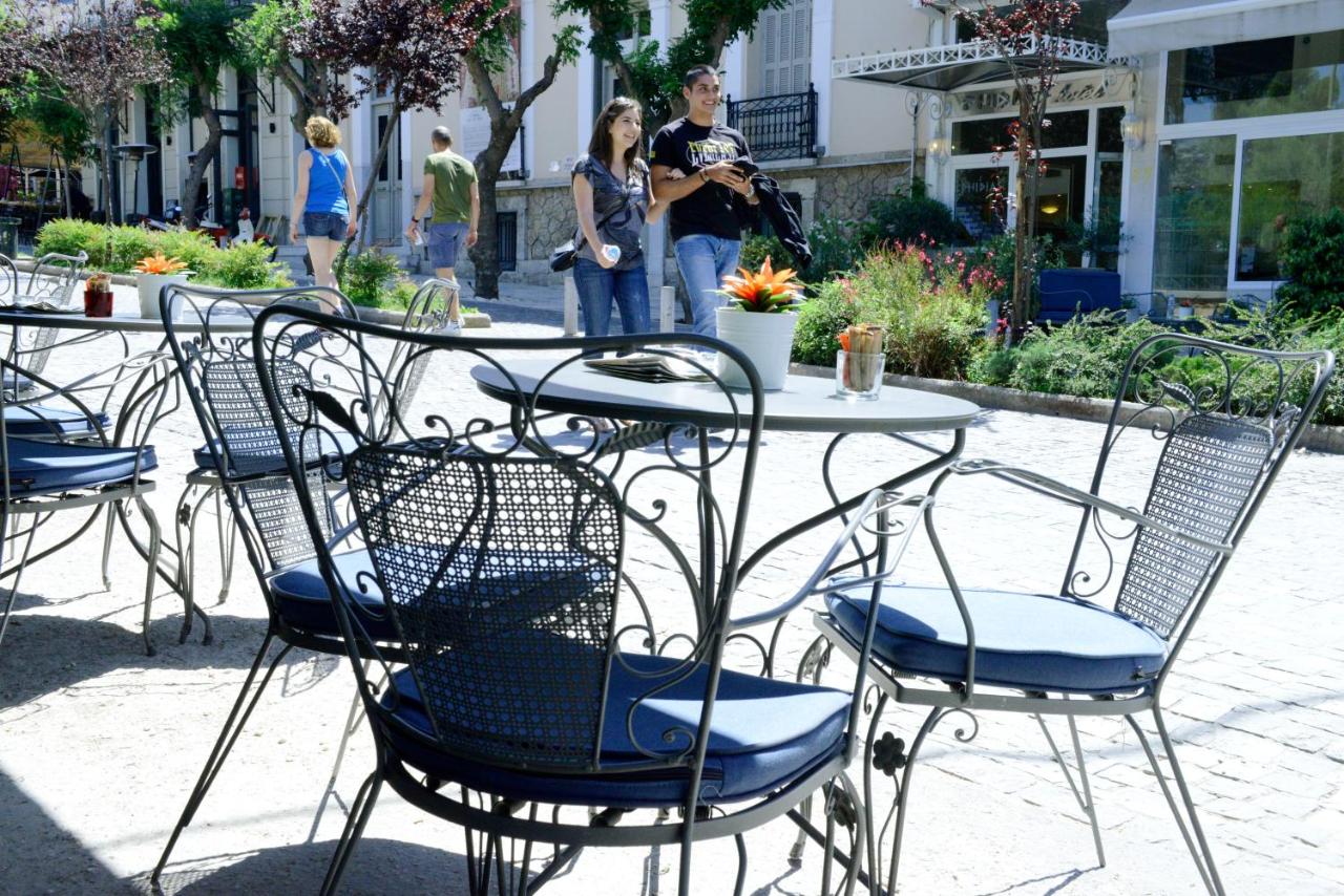 een tafel en stoelen met mensen die op de achtergrond staan bij Phidias Hotel by Oniro in Athene