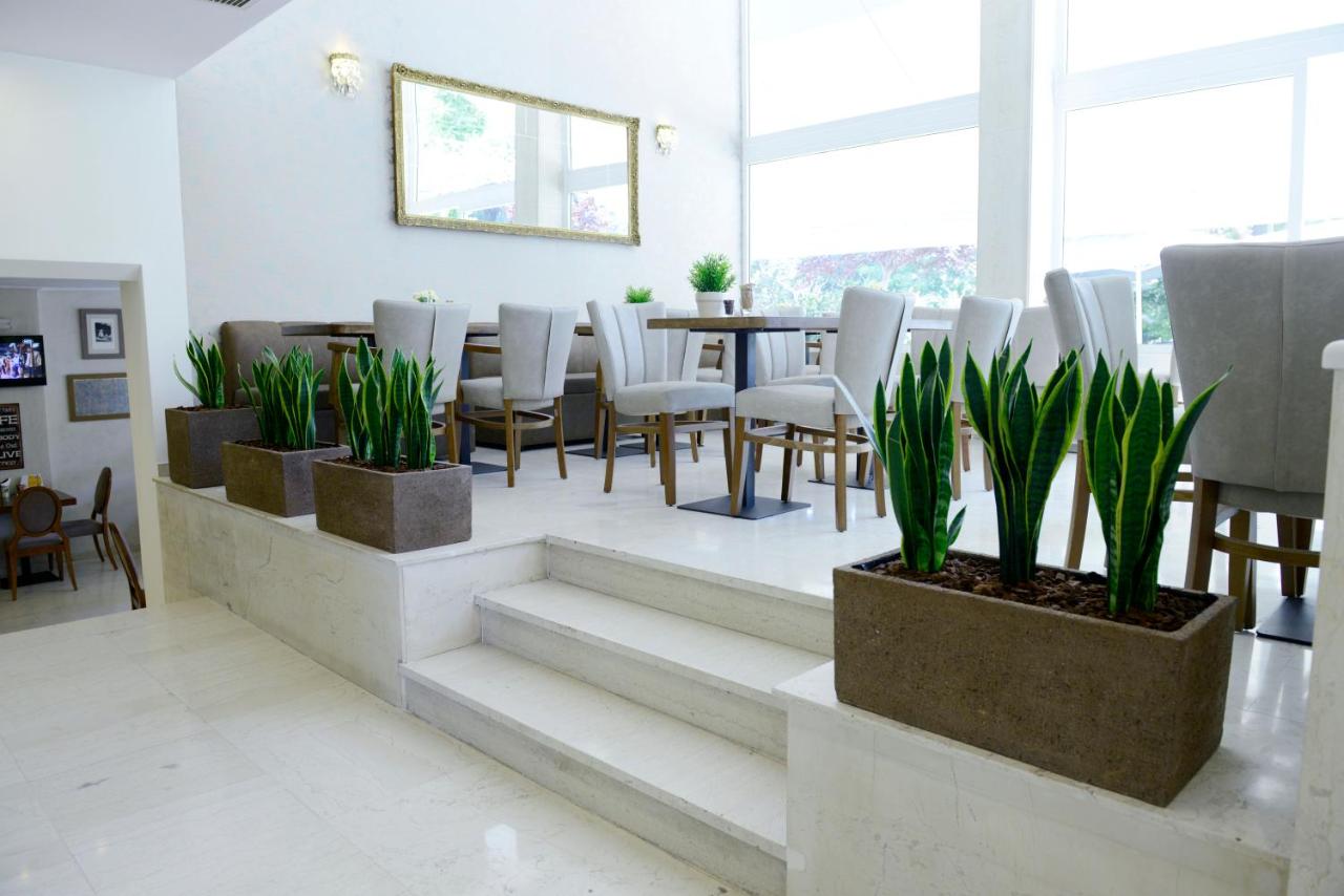 een eetkamer met een tafel, stoelen en planten bij Phidias Hotel by Oniro in Athene
