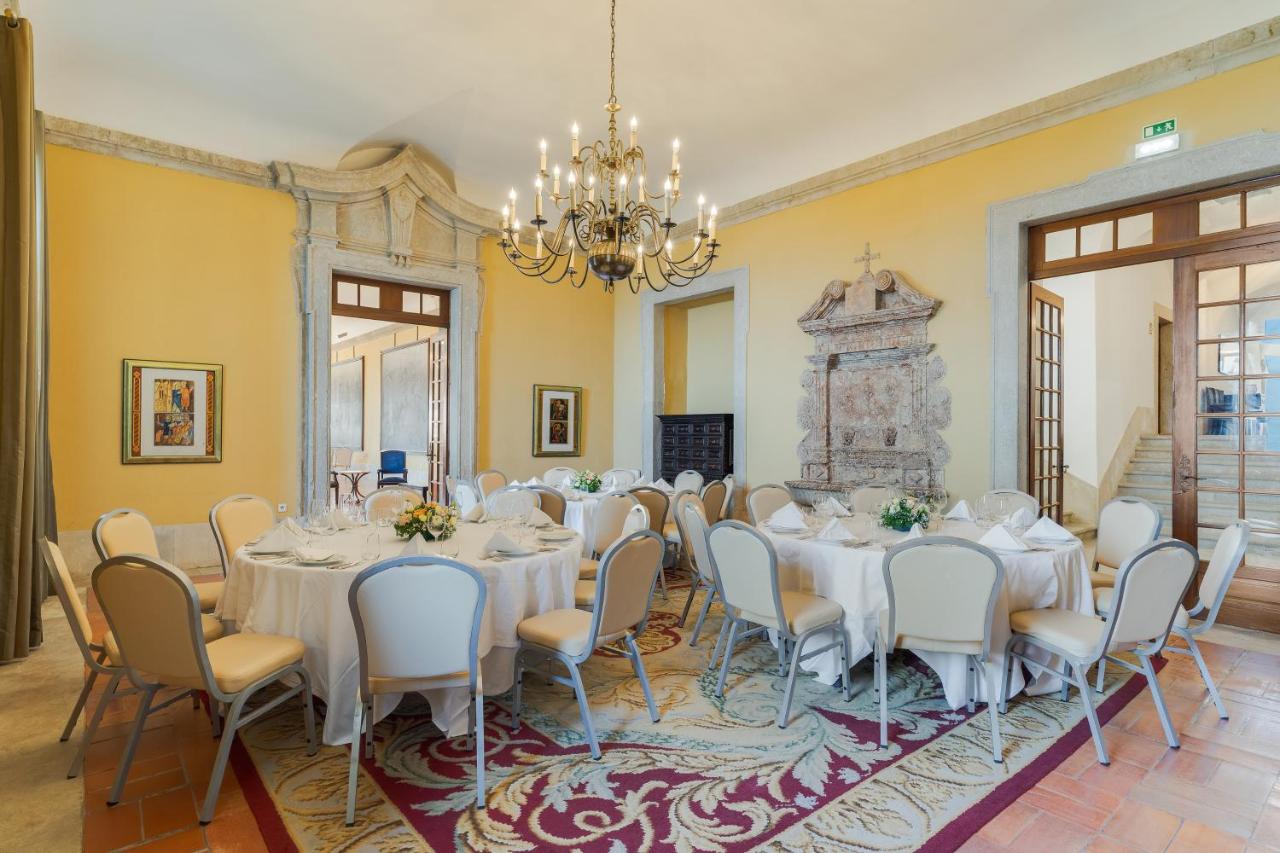 een grote kamer met tafels en stoelen en een kroonluchter bij Pousada Castelo de Palmela in Palmela