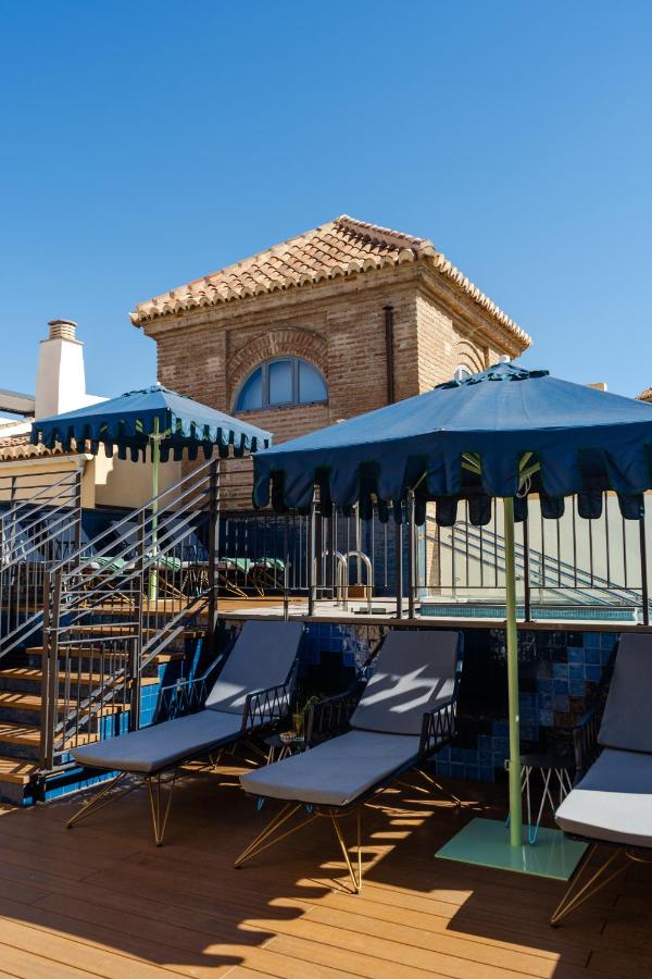 een groep stoelen en parasols naast een zwembad bij Palacio Solecio, a Small Luxury Hotel of the World in Málaga