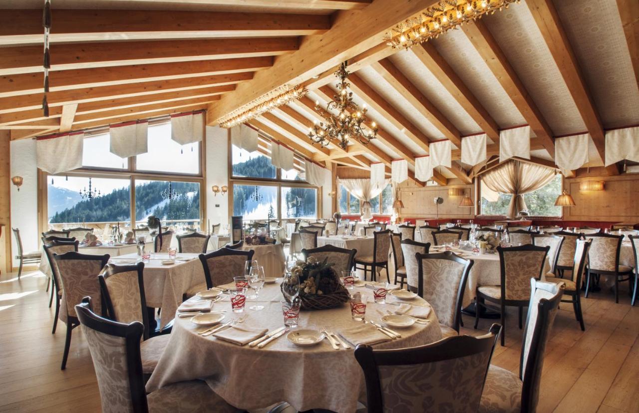 een eetkamer met tafels en stoelen en ramen bij Cristal Palace Hotel in Madonna di Campiglio