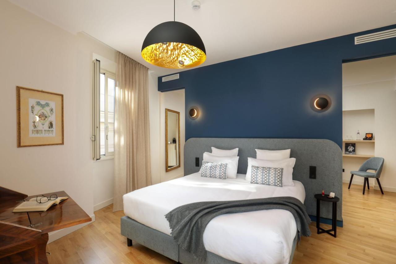 een slaapkamer met een groot bed en een blauwe muur bij 9Hotel Cesari in Rome