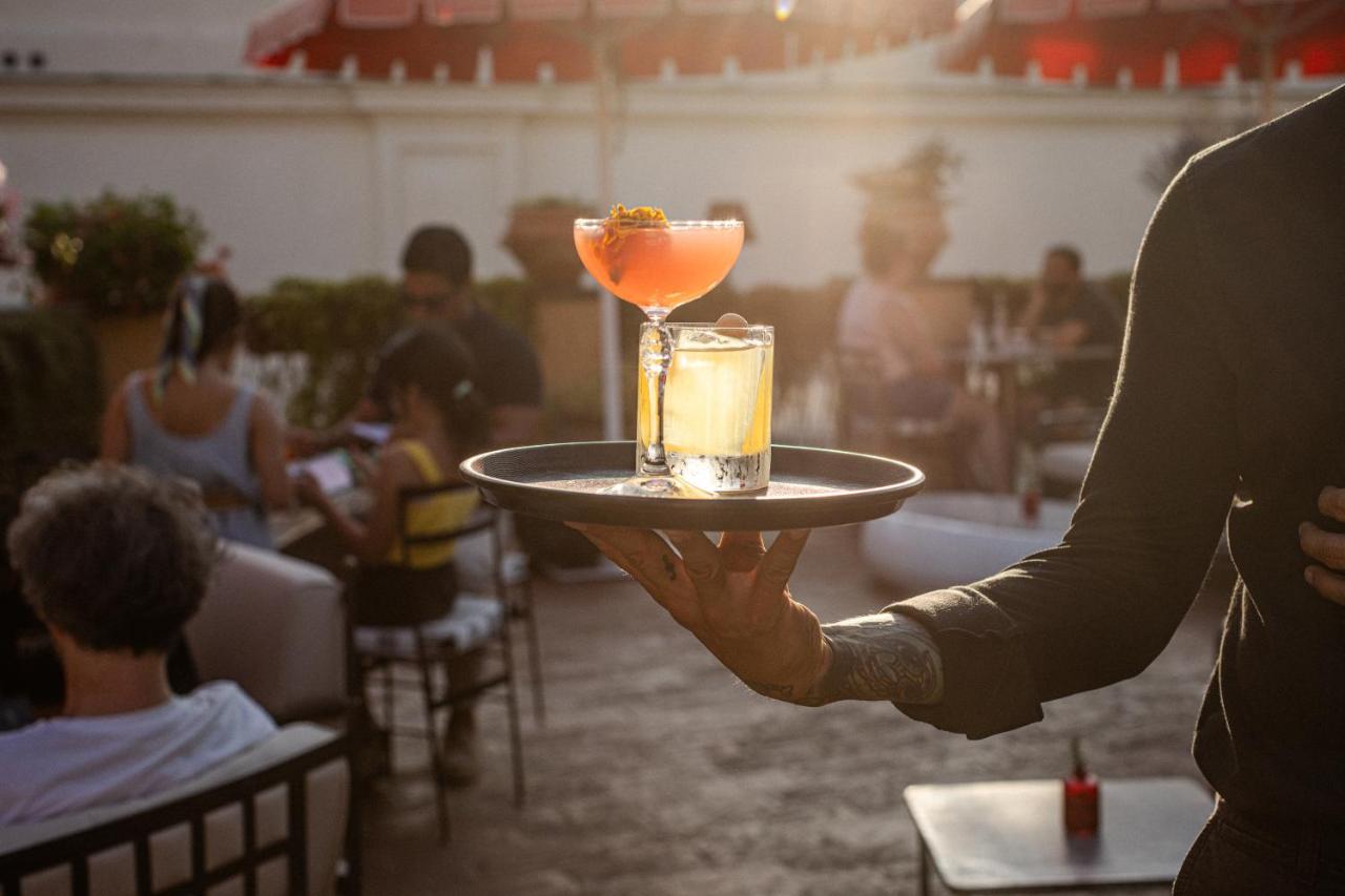 een persoon die een dienblad met een drankje erop vasthoudt bij 9Hotel Cesari in Rome