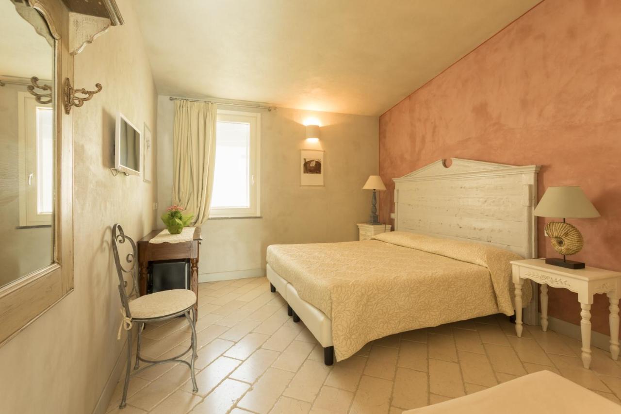 een slaapkamer met een bed, een stoel en een raam bij Il Cortiletto Hotel Maison in Tresnuraghes