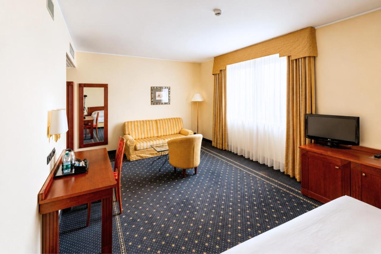 een hotelkamer met een bed, een bureau en een televisie bij Phi Hotel Cavalieri in Bra