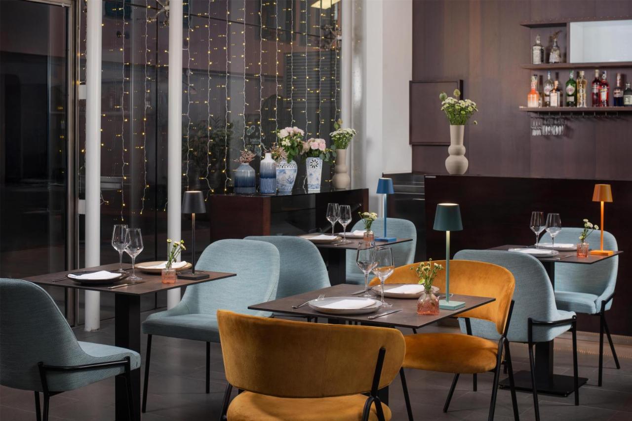 een restaurant met twee tafels en stoelen en bloemen bij NH Savona Darsena in Savona