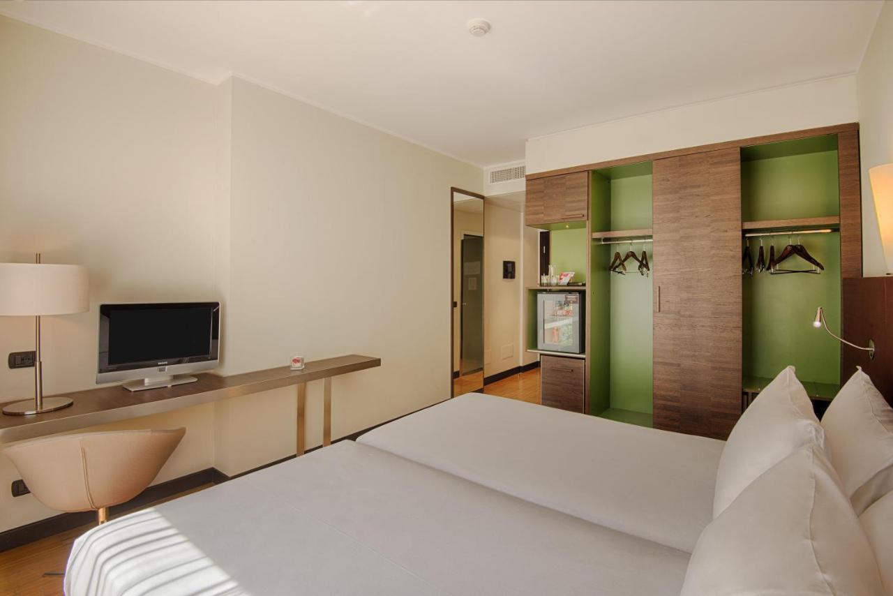 een hotelkamer met een bed en een televisie bij NH Savona Darsena in Savona