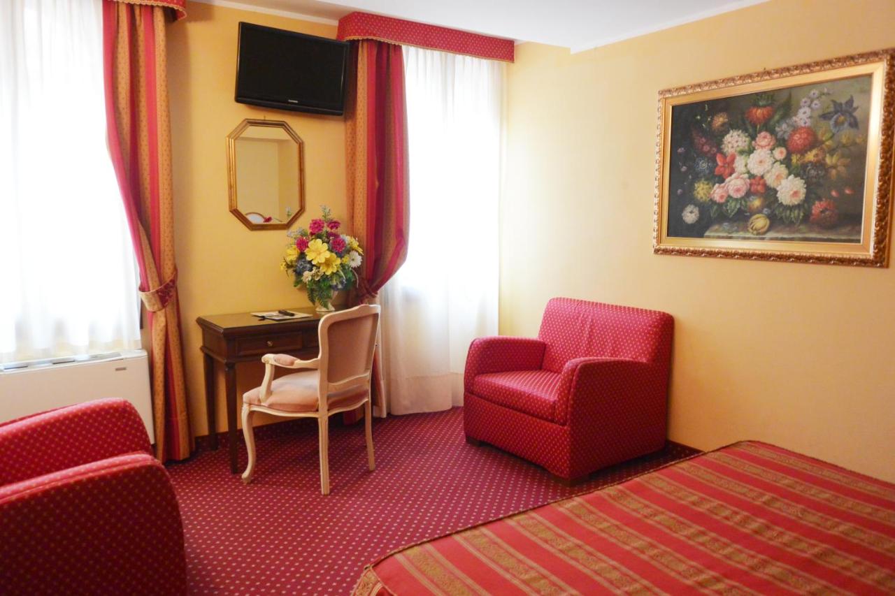 een hotelkamer met een rode stoel en een bureau bij Hotel Città Di Milano in Venetië