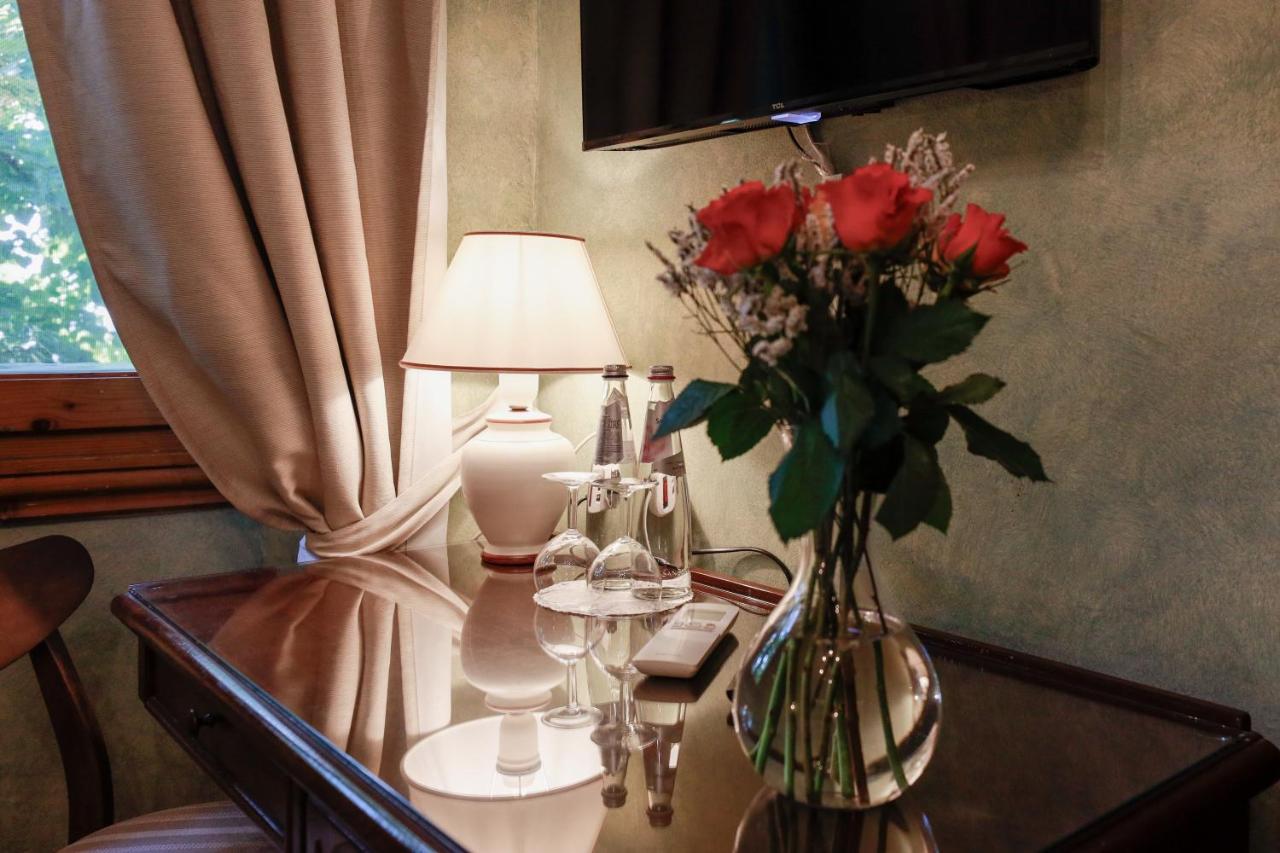 een vaas met rozen op een tafel met een lamp bij Hotel Bellavista Impruneta in Impruneta
