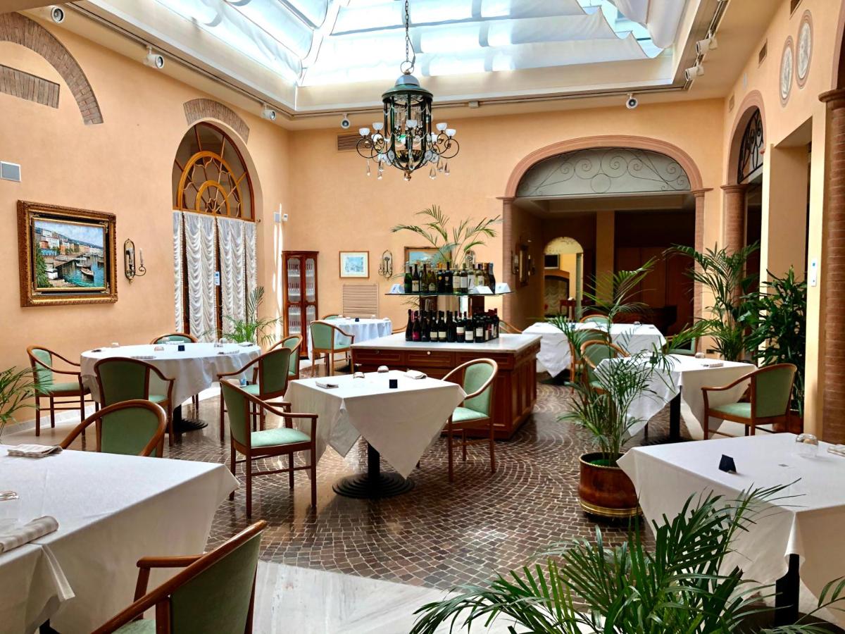 een restaurant met tafels en stoelen en een kroonluchter bij Phi Hotel Dei Medaglioni in Correggio