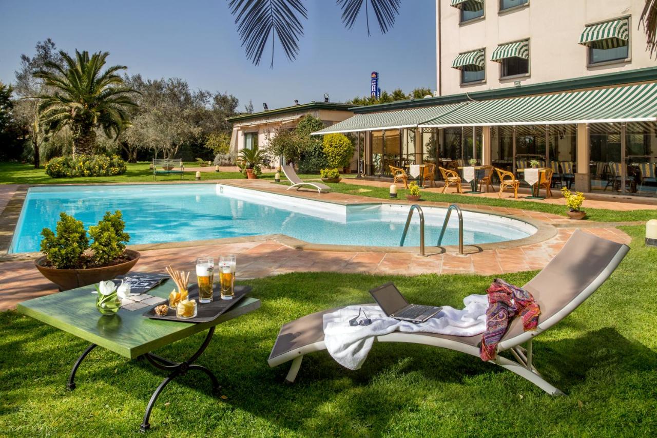 een zwembad met twee stoelen en een tafel in het gras bij Best Western Park Hotel Roma Nord in Fiano Romano