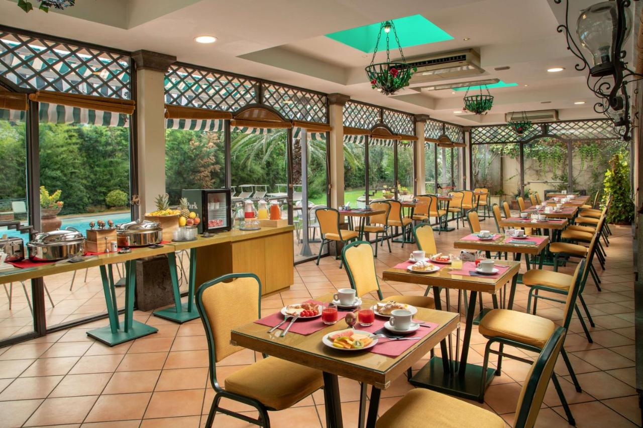 een restaurant met tafels, stoelen en ramen bij Best Western Park Hotel Roma Nord in Fiano Romano