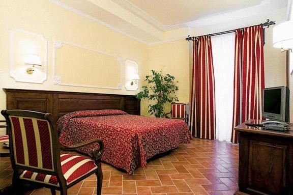 een slaapkamer met een bed, een stoel en een televisie bij Hotel California in Florence