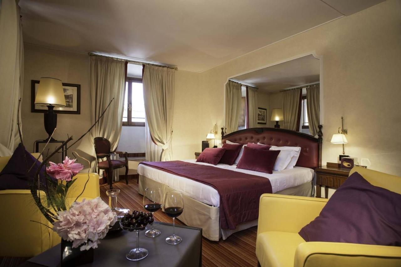 een hotelkamer met een groot bed en een bank bij Colonna Palace Hotel in Rome