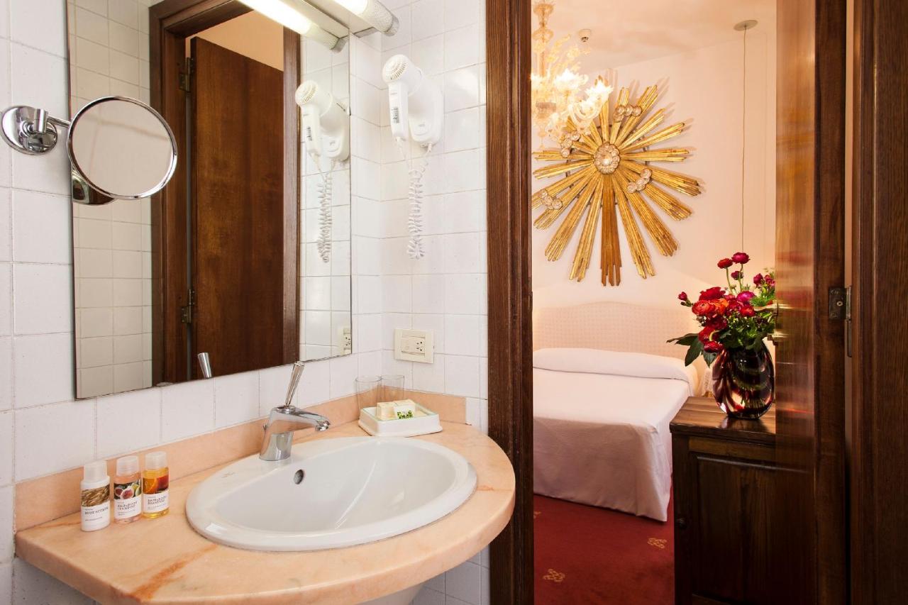 een badkamer met een wastafel, een spiegel en een bed bij Hotel Columbia in Rome