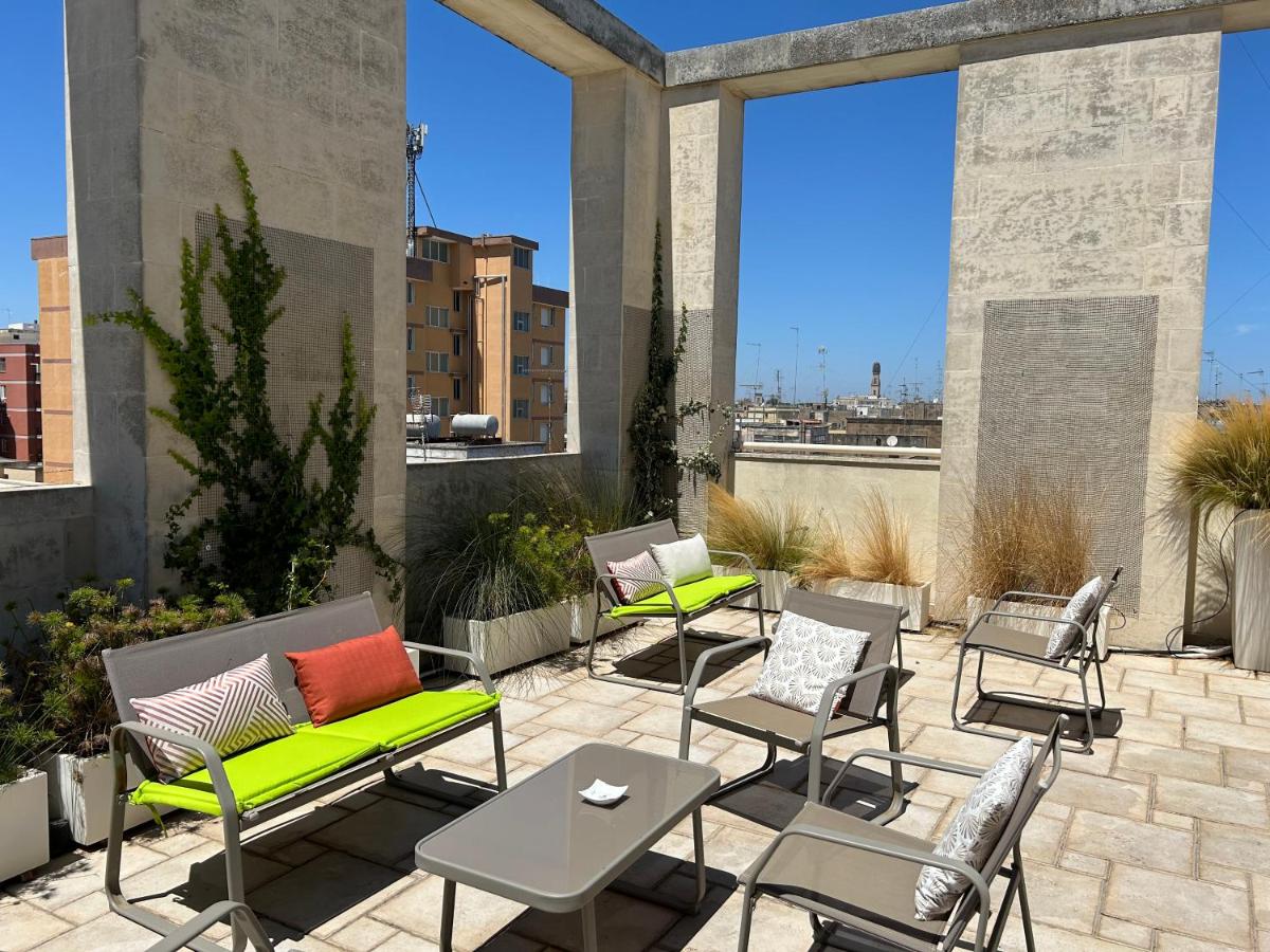 een terras met stoelen en tafels en grote ramen bij Eos Hotel in Lecce