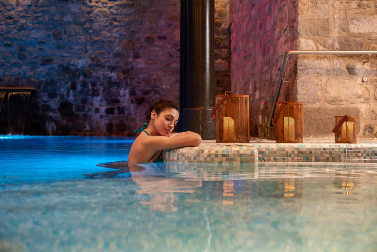 Een vrouw zit in een zwembad. bij Hotel Helvetia Thermal SPA 4s in Porretta Terme