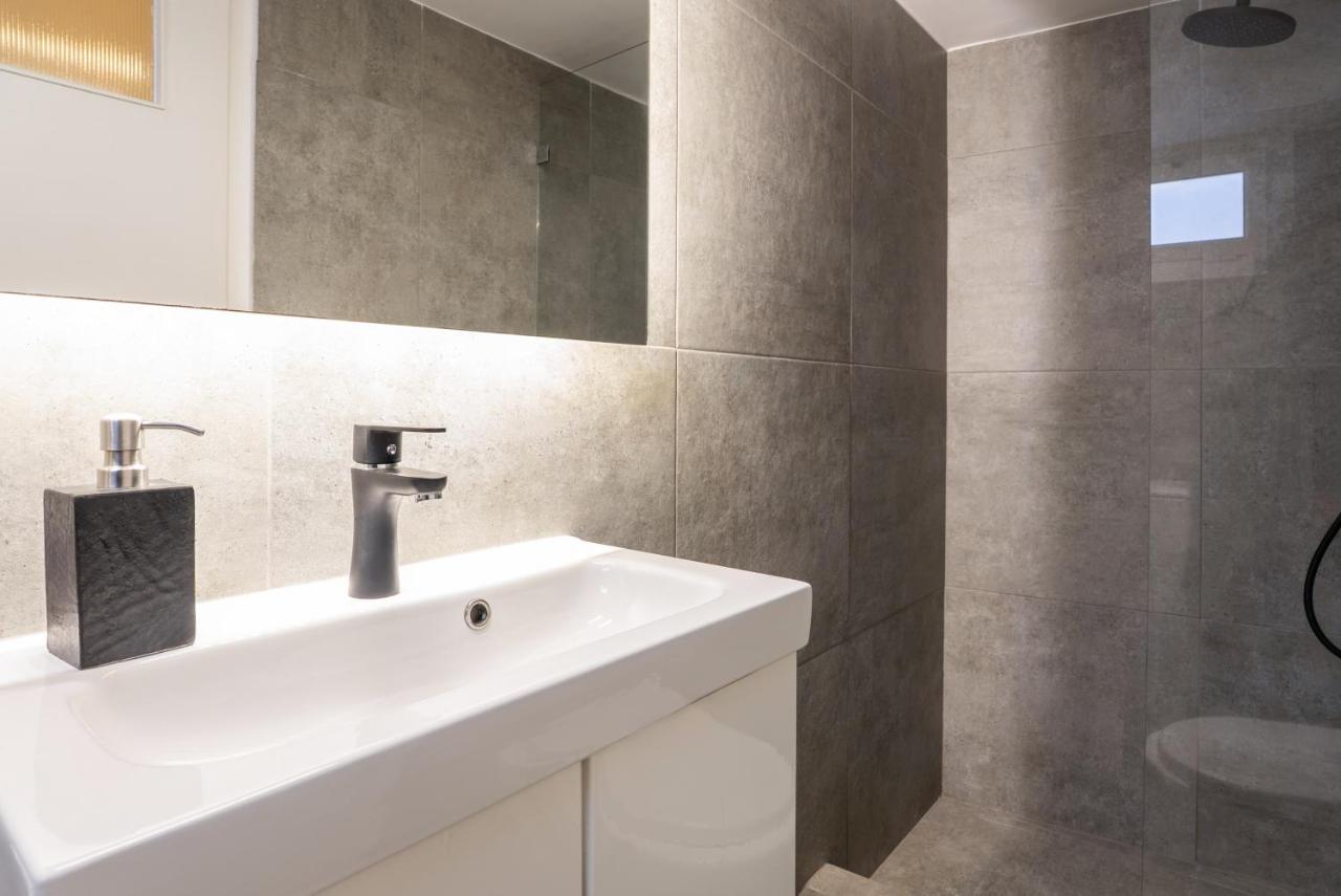 een badkamer met een witte wastafel en een spiegel bij Athens Urban Nest in Athene