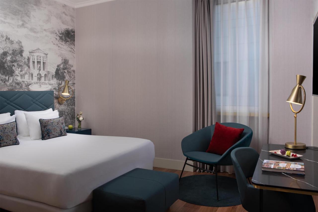 een hotelkamer met een bed, een bureau en een stoel bij NH Collection Roma Fori Imperiali in Rome