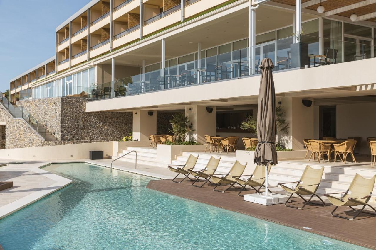 een zwembad met stoelen en een parasol naast een gebouw bij Divani Corfu Palace in Corfu-stad