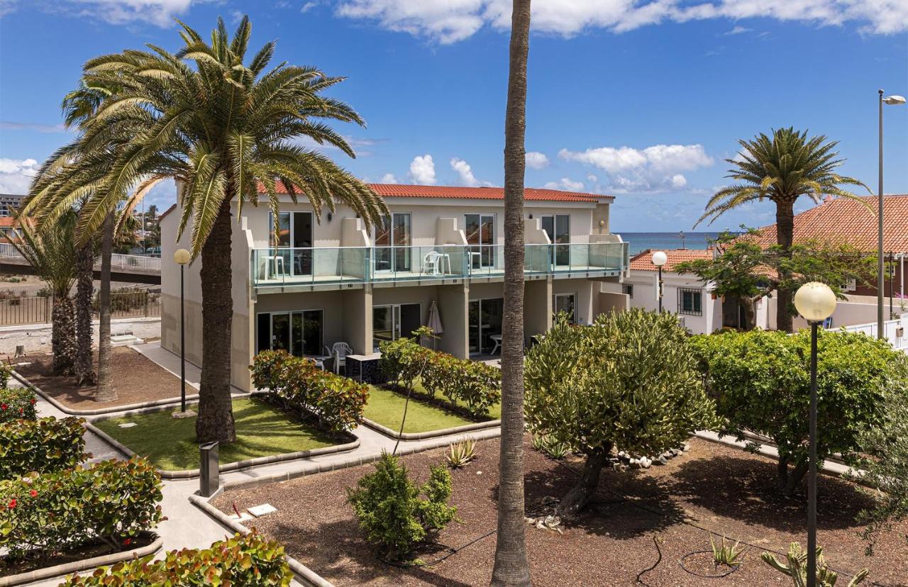 een gebouw met palmbomen en de oceaan op de achtergrond bij Smartr Maspalomas Corinto in Playa del Inglés