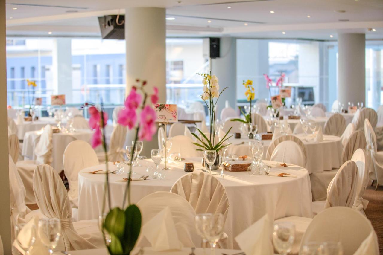een kamer met witte tafels en stoelen versierd met bloemen bij Blue Lagoon Kosher Hotel (by Capital Coast Resort & Spa) 
