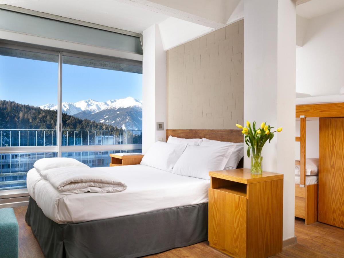 een slaapkamer met een bed en een groot raam bij TH Marilleva in Mezzana