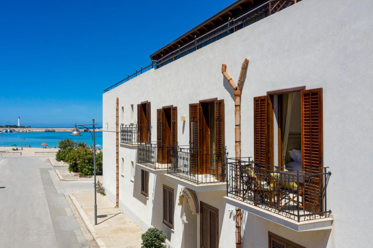 een wit gebouw met bruine luiken en een balkon bij Mira Spiaggia in San Vito lo Capo +117 foto's