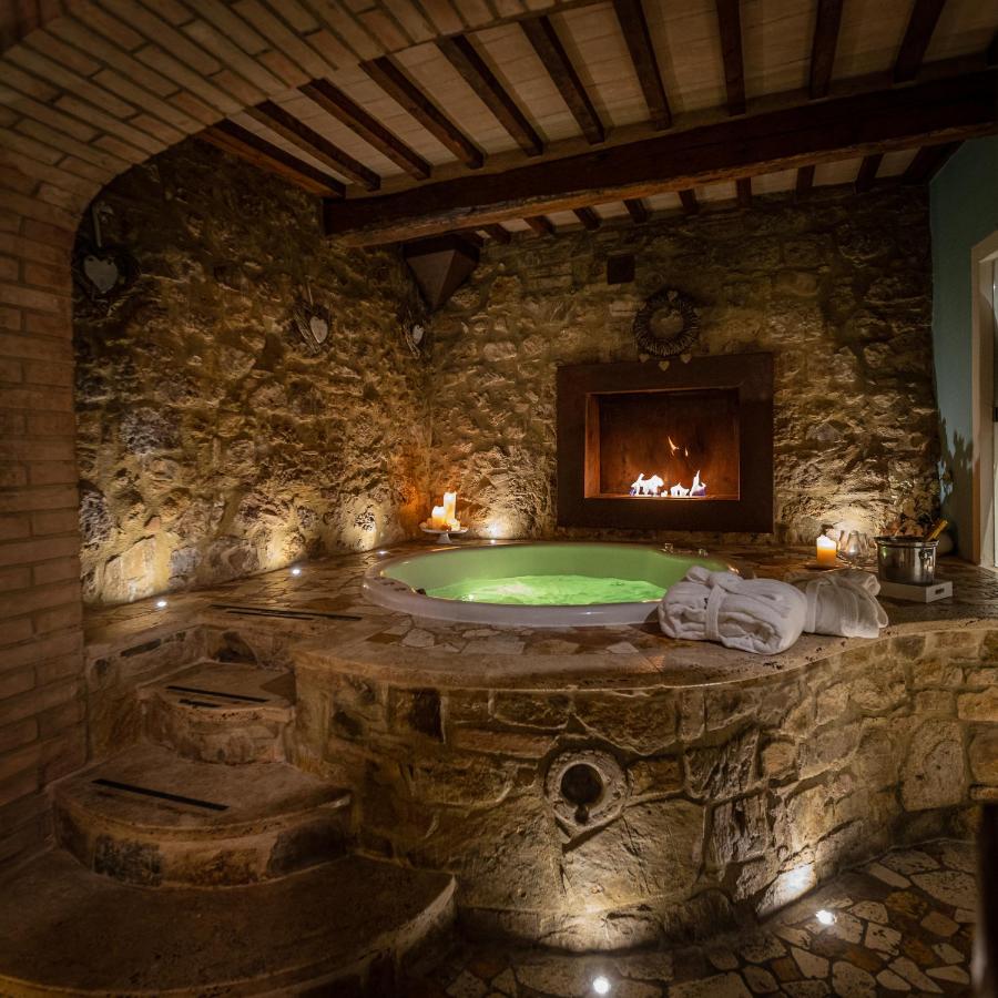 een stenen badkamer met een badkuip en een open haard bij PALAZZO DEL CAPITANO Wellness & Relais - Luxury Borgo Capitano