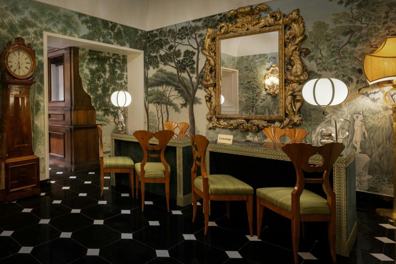 een kamer met een spiegel, stoelen en een klok bij Hotel d’Inghilterra Roma – Starhotels Collezione in Rome