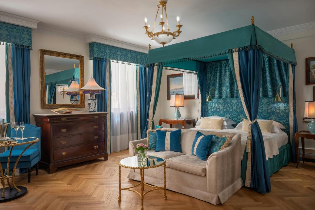 een slaapkamer met een hemelbed en een bank bij Hotel d’Inghilterra Roma – Starhotels Collezione in Rome