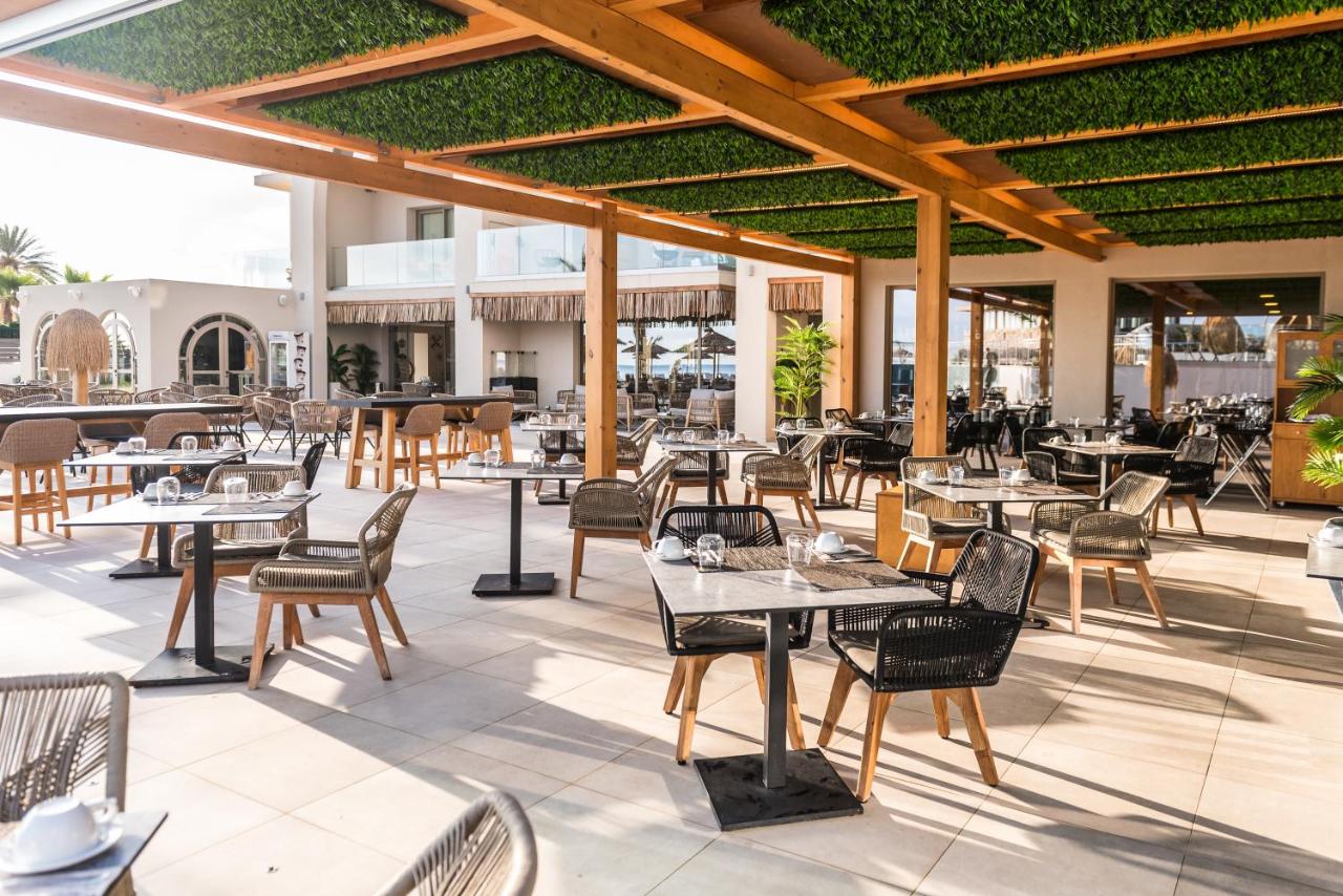 een buitenterras met tafels, stoelen en een tafelblad bij Pepper Sea Club Hotel in Georgioupolis