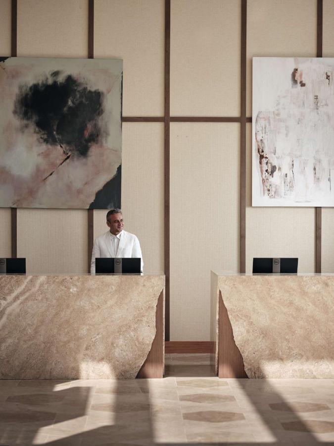 een man zit aan een bureau met een laptop bij The Royal Senses Resort & Spa Crete, Curio Collection by Hilton in Panormo