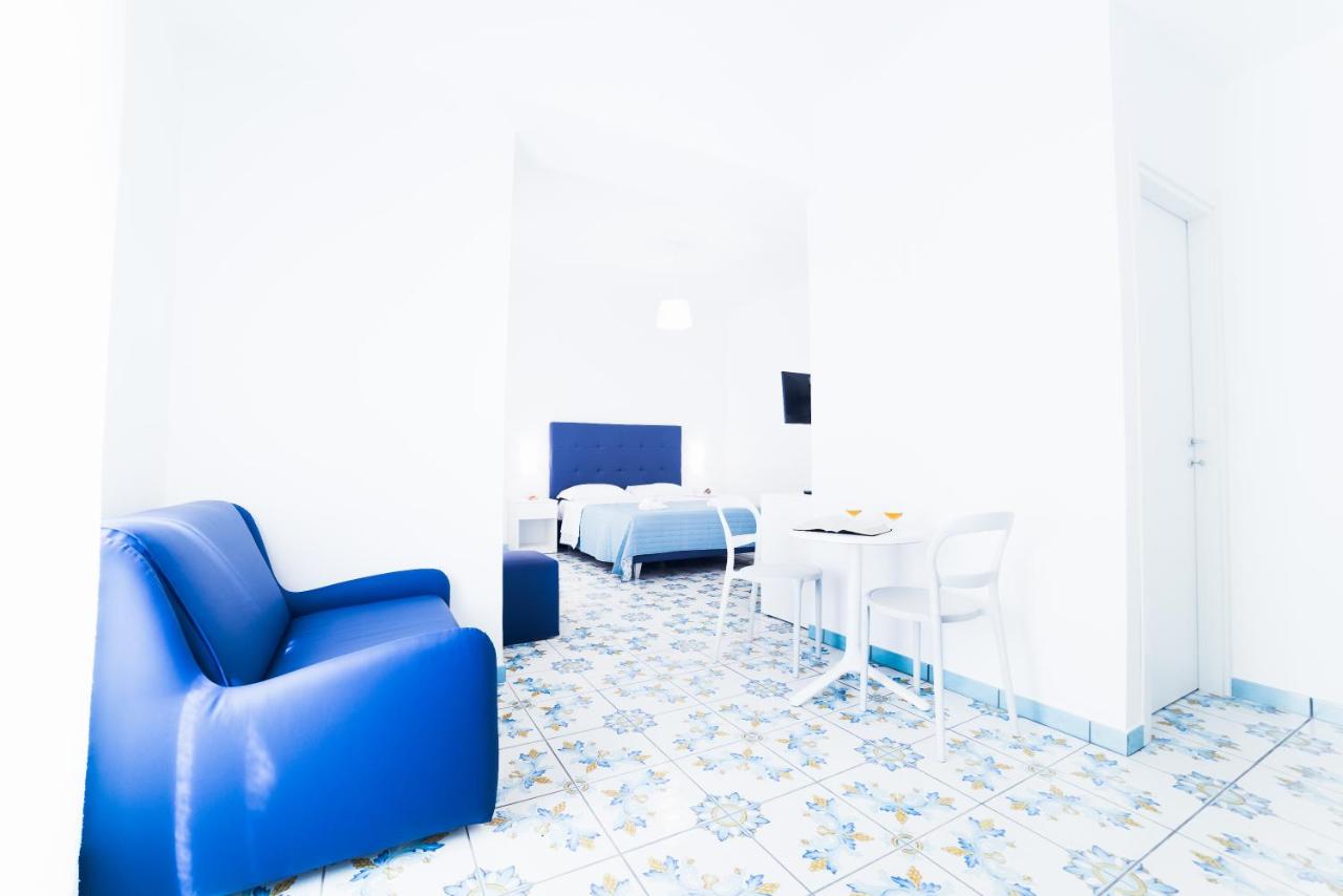 een kamer met een blauwe stoel, een tafel en een bed bij La Casa di Aurora in Maiori