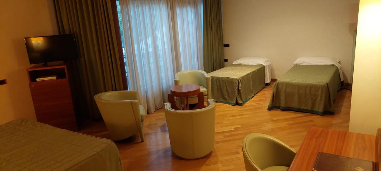 een kamer met twee bedden en een tafel en stoelen bij Solofra Palace Hotel & Resort in Solofra