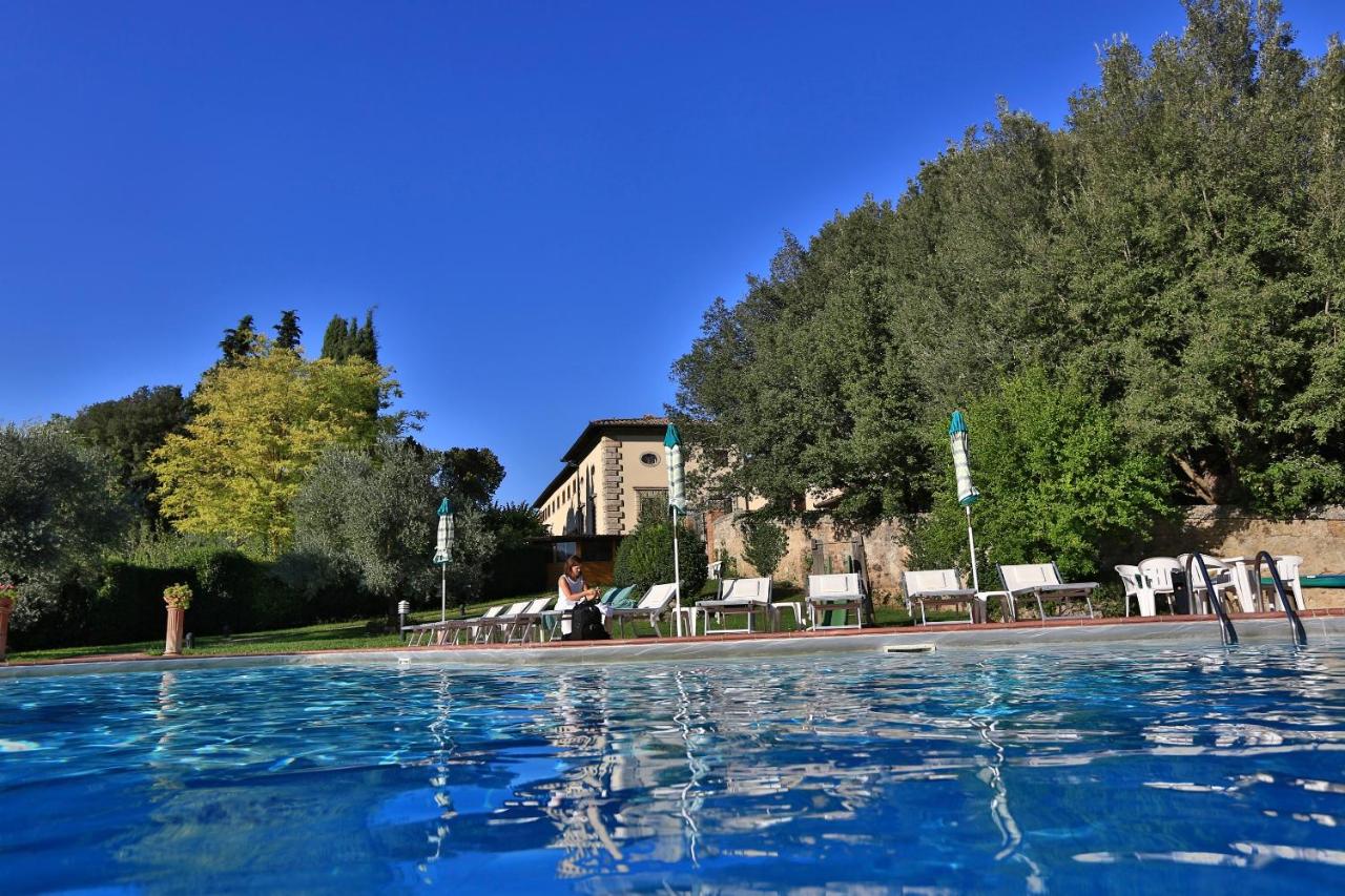 een zwembad met ligstoelen en een gebouw op de achtergrond bij Hotel Villa San Lucchese in Poggibonsi
