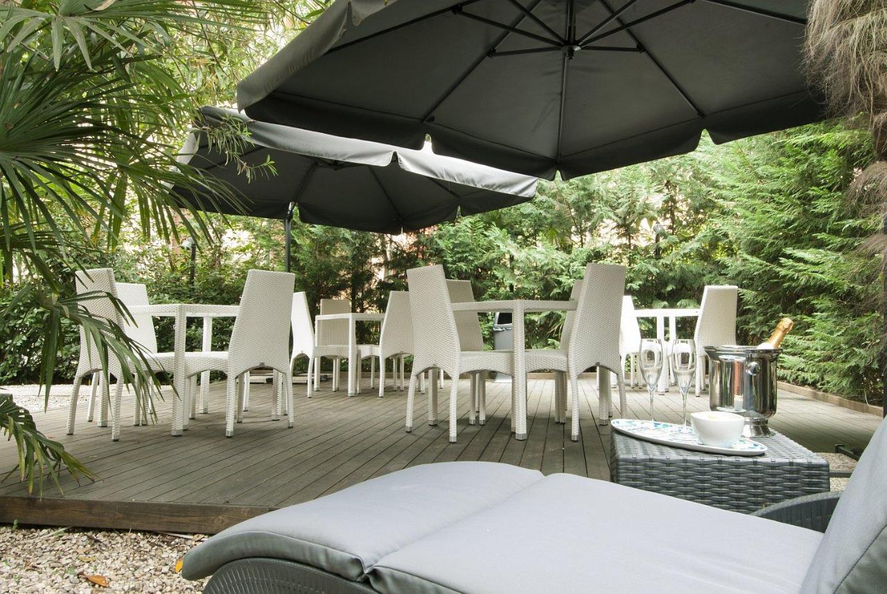 een aantal stoelen en een parasol op een terras bij Hotel Villa Pannonia in Venetië-Lido