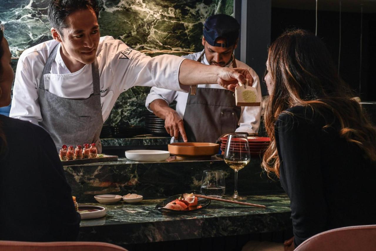 een chef-kok die eten bereidt op een tafel in een restaurant bij Sina De La Ville in Milaan