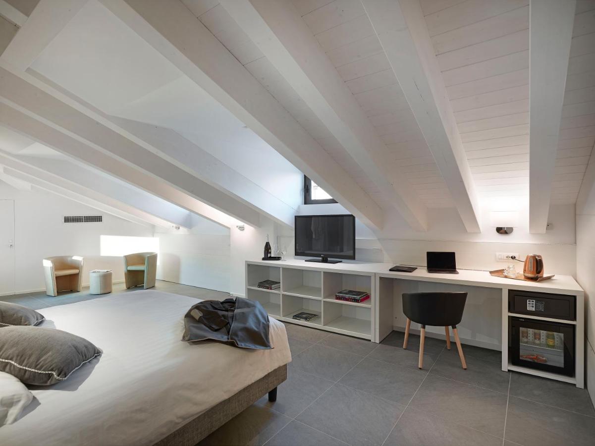 een slaapkamer met een bed en een bureau met een tv bij Boutique Hotel Touring in Verona