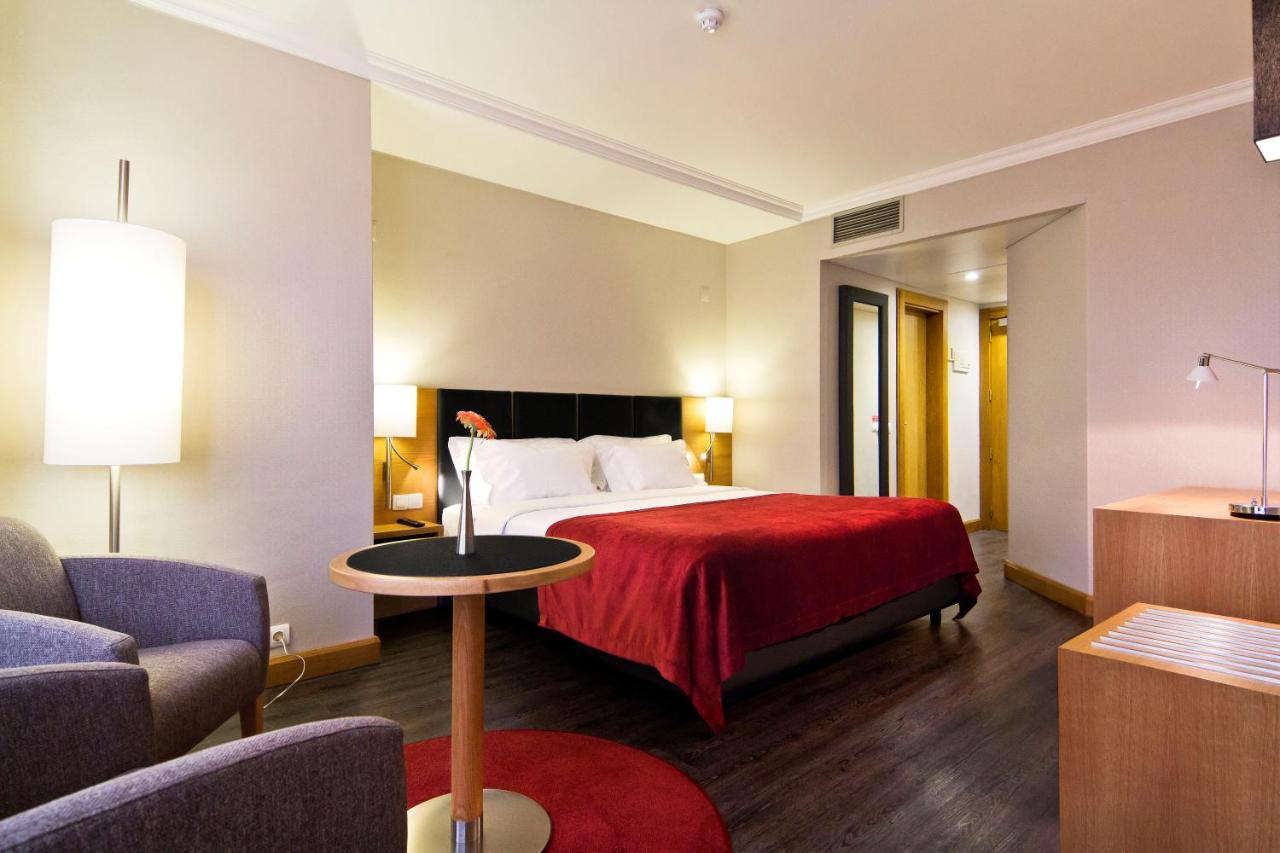 een hotelkamer met een bed met een rode deken bij SANA Reno Hotel in Lissabon