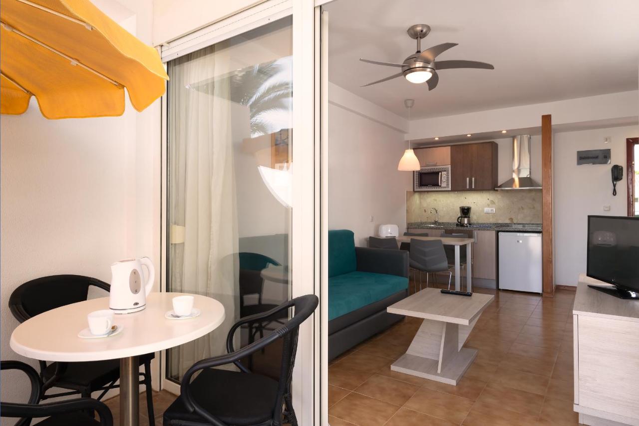 een woonkamer en keuken met een tafel en stoelen bij Apartamentos Montemayor in Playa del Inglés