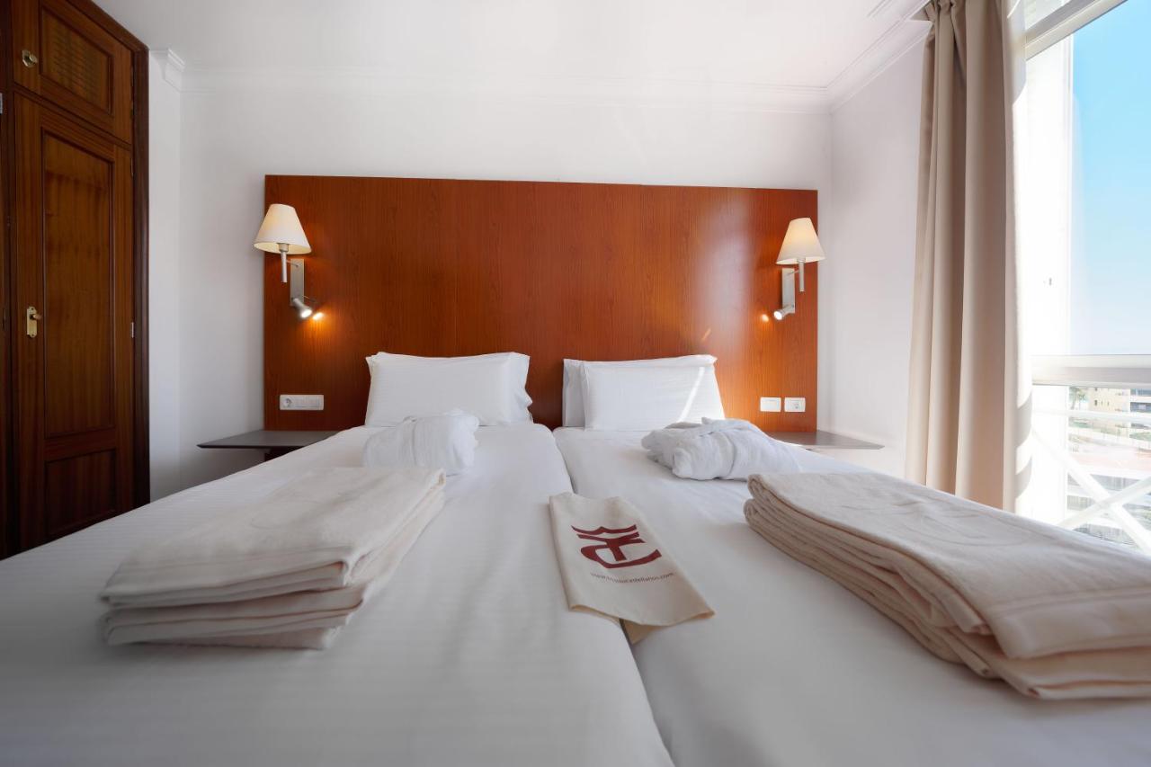 een wit bed met witte lakens en handdoeken erop bij TC Apartamentos Dorotea in Playa del Inglés