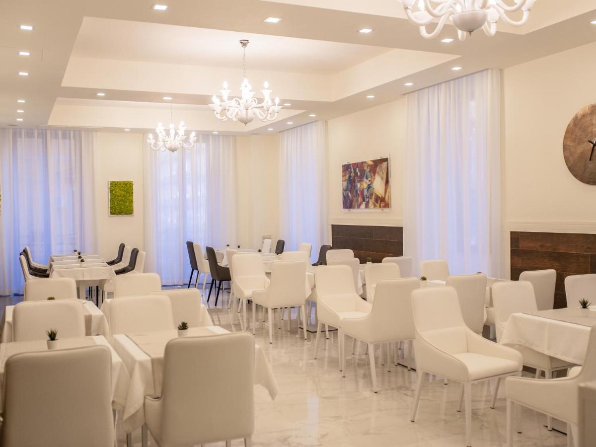 een kamer met witte stoelen en tafels en een kroonluchter bij Palazzo Firenze in Napels