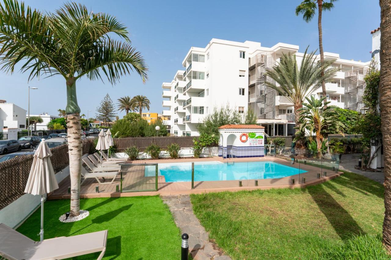 een zwembad met palmbomen en een gebouw bij Alsol El Chaparral in Playa del Inglés