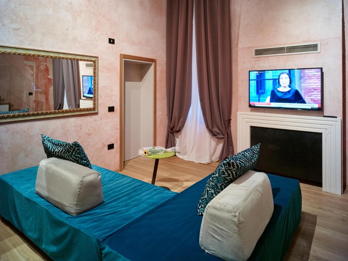een woonkamer met een bed en een flatscreen-tv bij Ca' dei Proverbi Suites - WENICE Deep Culture in Venetië