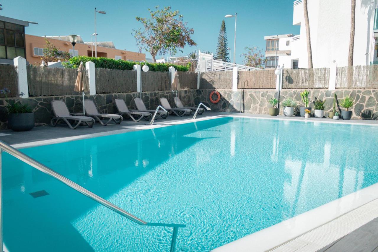 een blauw zwembad met stoelen en een hek. bij Apartamentos El Palmar in Playa del Inglés