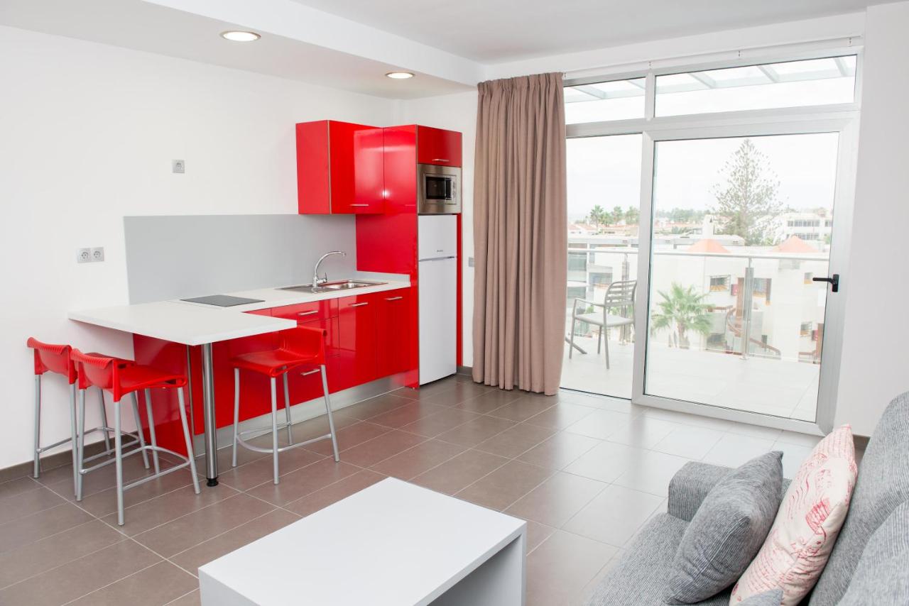 een keuken met rode kasten en een tafel in een kamer bij Apartamentos El Palmar in Playa del Inglés