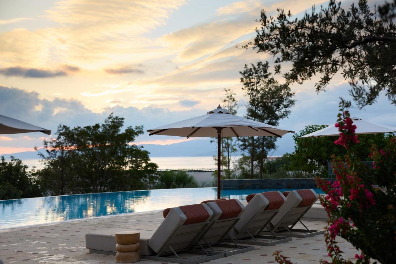 een groep stoelen en parasols naast een zwembad bij Elounda Gulf Villas by Sandglass in Elounda